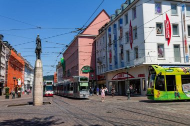 Bir grup insan, Freiburg, Almanya ve Avrupa şehir merkezinden geçen tramvaylarla sokakta yürüyor.