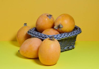 Sarı arka planda küçük bir hasır sepette medyanların yakın çekimi.