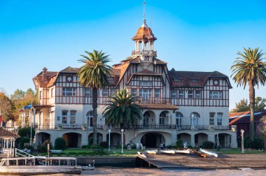 Nehrin kıyısında, etrafında palmiye ağaçları olan bina.