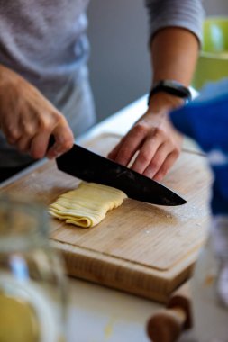 Mutfakta bıçakla hamuru kesen birinin dikey görüntüsü.