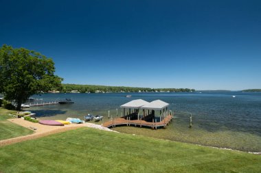 Güneşli bir günde güzel bir göl manzarası ve bahçeden gelen tekneler.