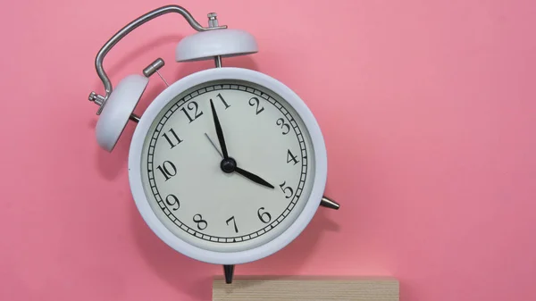 ピンクの背景に白い目覚まし時計に焦点を当てます 時間を無駄にできないことを示す白い目覚まし時計 — ストック写真