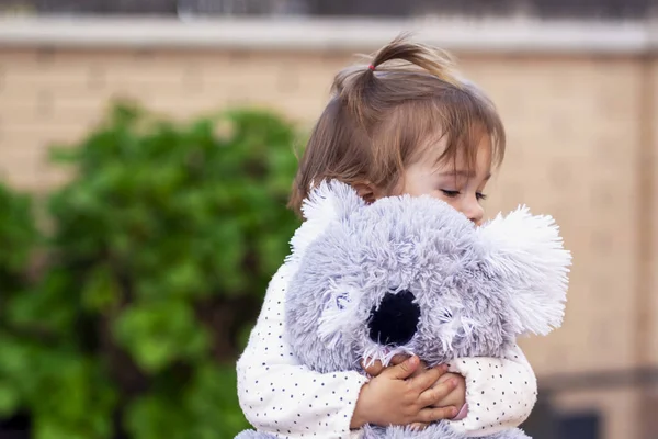 Mutlu kız oyuncak ayısına sarılıyor.