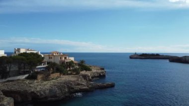 İspanya 'nın Mallorca sahilinde deniz suyu ve ufukta mavi gökyüzü manzaralı evler.