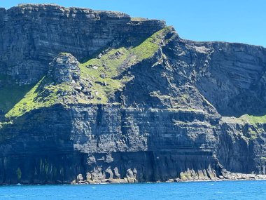 Güneşli bir günde mavi gökyüzüne karşı İrlanda 'daki Moher Uçurumlarının havadan görünüşü
