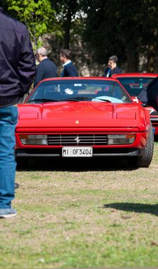 Kırmızı Ferrari 'nin dikey görüntüsü bir araba fuarında sergileniyor.