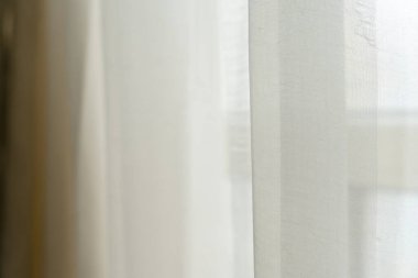 Pencereden sarkan beyaz güzel perdelerin yakın çekimi.