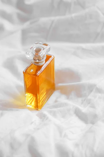 白いベッドシートの上の高級香水瓶の垂直ショット — ストック写真