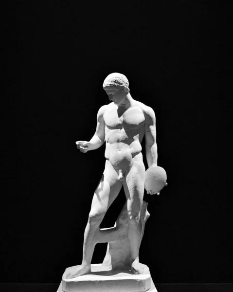 A vertical shot of the Discophoros sculpture on a black background