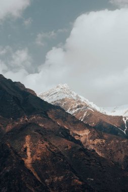 Bulutlu gökyüzüne karşı kar kaplı güzel dağların büyüleyici manzarası