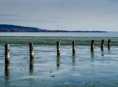 Bir bahar ya da yaz günü kumdaki ahşap oyların olduğu bir deniz ya da okyanus manzarası