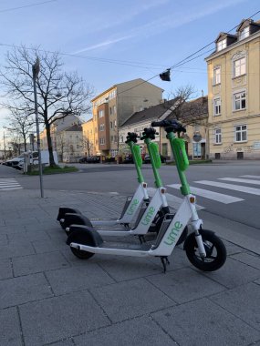 Güneşli bir bahar gününde Linz 'de yol kenarına park etmiş elektro scooterların dikey çekimi.