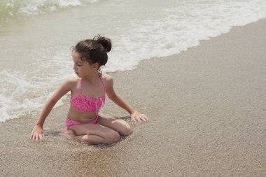 Pembe bikinili kız güneşli bir yaz gününde kumsalda dalgalarla mutlu mesut oynuyor, Vera, İspanya