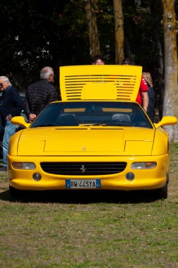 Bir araba fuarında sergilenen sarı bir Ferrari 'nin dikey çekimi.