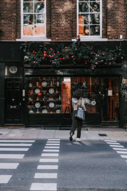 Londra, İngiltere 'de bir taşın yanında çantalı bir kadının dikey görüntüsü.