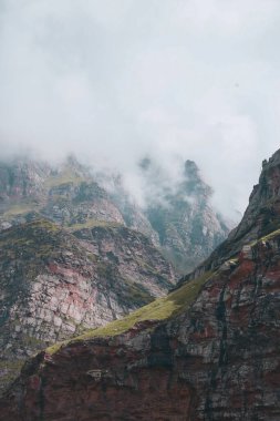 Kırsal alanda bulutlarla çevrili kayalık dağların dikey görüntüsü