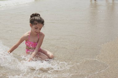 Pembe bikinili kız güneşli bir yaz gününde kumsalda dalgalarla mutlu mesut oynuyor, Vera, İspanya