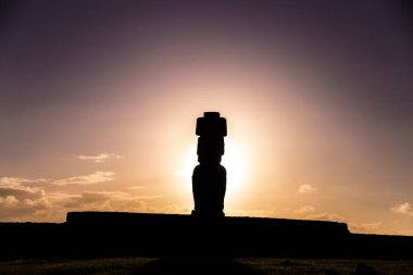 Şili, Paskalya Adası 'nda, bulutlu bir günbatımına karşı antik bir Moai taş heykeli manzarası.