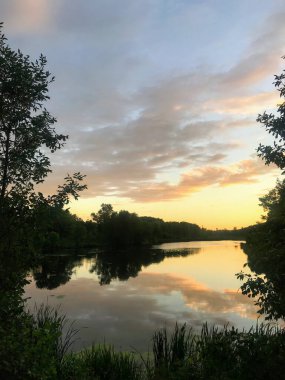 Gölde yansıyan renkli bulutlarla Kunduz Göleti Yolu 'nun güzel gün batımı manzarası.