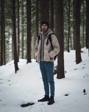 Karlı bir ormanda duran bir adamın yakın çekimi.