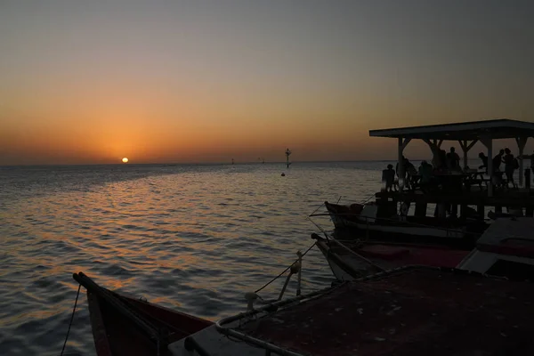 Silhouette Tourists Dock Popular Seaside Restaurant Watching Sun Brilliant Orange — Stock Photo, Image