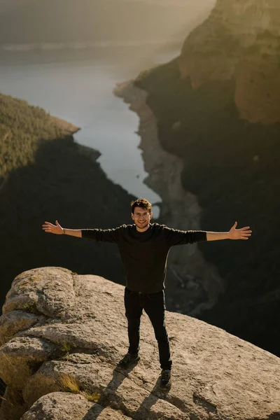 一个年轻的西班牙裔男子站在一块巨大的岩石上 张开双臂的垂直镜头 — 图库照片