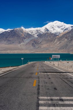 Arka planda dağlar olan bir rıhtım yolunun dikey çekimi.