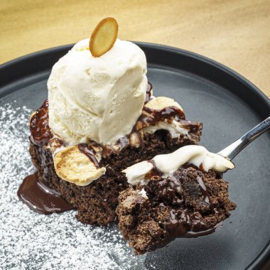 Dondurmalı Brownie 'nin siyah tabakta çikolatalı şekerlemeyle yakın plan fotoğrafı.