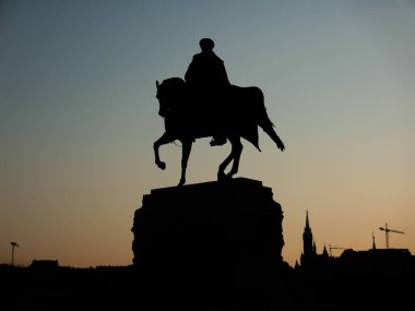 Güneş doğarken binicilik heykelinin silueti.