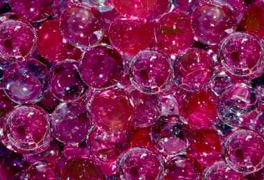 Yakın planda birçok mor kırmızı şeffaf toplar