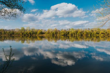Güneşli bahar gününde suyun üzerindeki bulut yansımaları