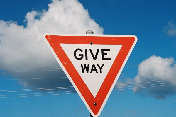 A closeup shot of the Give Way sign against a blue cloudy sky