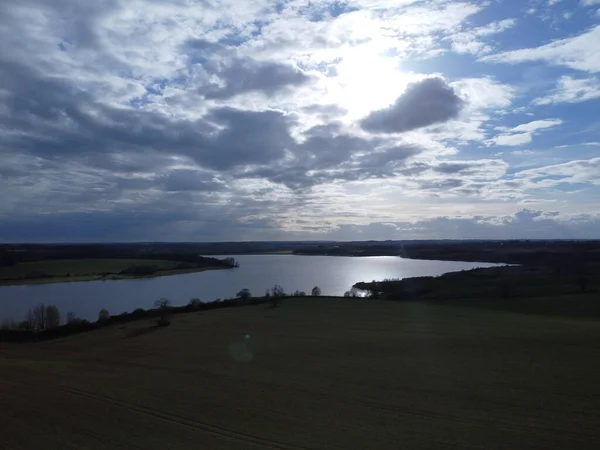 ピッツフォード貯水池 ノースアンプトンシャー イングランドで明るい光沢のある太陽と青い曇り空の下で湖と緑の牧草地の美しい風景 — ストック写真