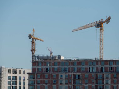 Mavi gökyüzü arka planında iki vinç olan eski yerleşim yerleri manzarası.