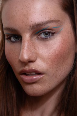 Yüzünde çilleri ve makyajı olan Avustralyalı bir kız.