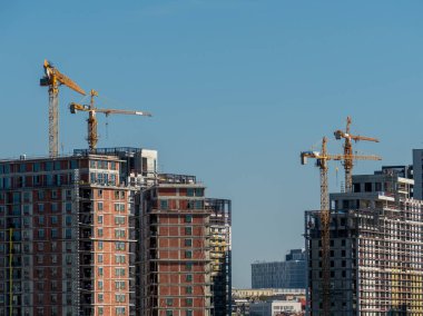 Yüksek modern konut manzarası ve vinçlerle devam eden bir inşaat.