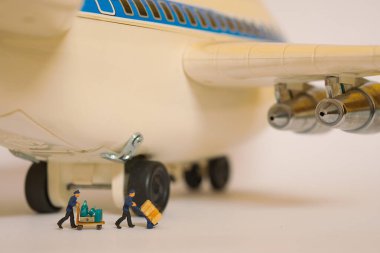 Büyük bir uçağın önünde bavul taşıyan işçiler.