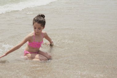 Pembe bikinili kız güneşli bir yaz gününde kumsalda dalgalarla mutlu mesut oynuyor, Vera, İspanya