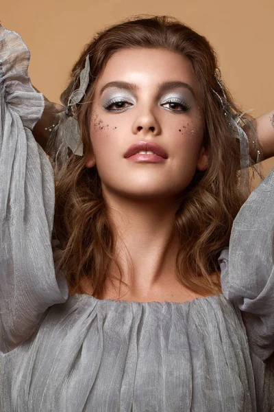 A portrait of a young caucasian girl with makeup and a bow in the hair