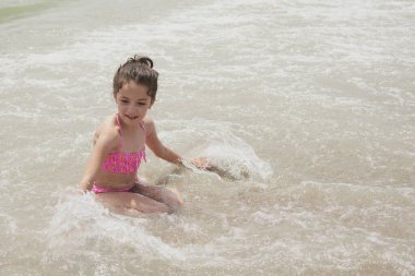 Pembe bikinili kız güneşli bir yaz gününde kumsalda dalgalarla mutlu mesut oynuyor, Vera, İspanya