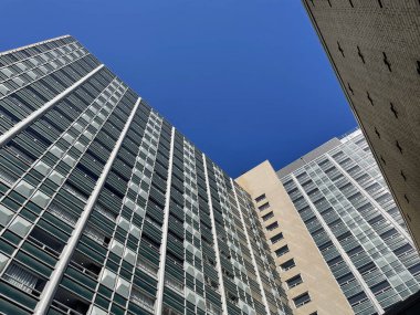 Modern bir binanın, parlak güneş ışığında mavi gökyüzüne karşı alçak açılı görüntüsü.