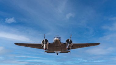 Amelia Earhart 'ın uçağı Lockheed Electra mavi gökyüzünün arka planında uçuyor.