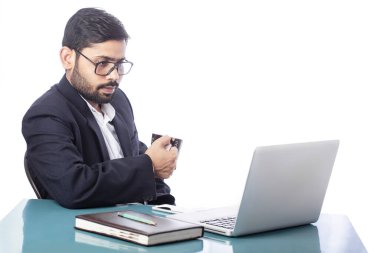 İş adamı kahve içiyor ve izole edilmiş arka planda dizüstü bilgisayar ekranına bakıyor.