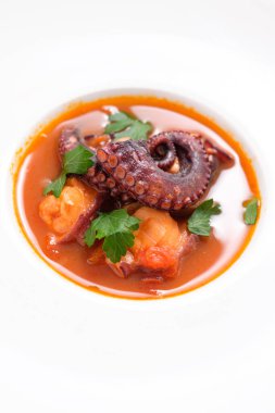 Maydanozlu domates çorbasında pişirilmiş ahtapot resmi.