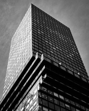 Cam pencereli bir gökdelenin dikey düşük açılı gri ölçekli görüntüsü