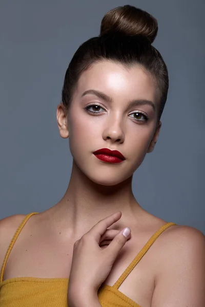 A portrait of a Caucasian female with hair in a bun and red lips