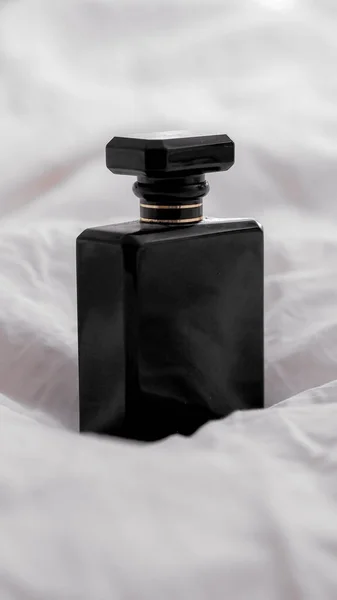 白いシートの上に黒香水のボトルのクローズアップショット — ストック写真