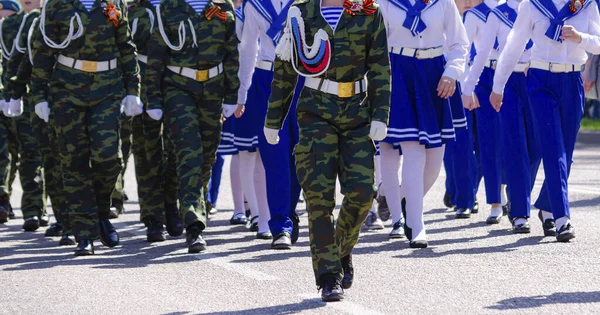 迷彩服を着た若者のグループ兵士と船員の青と白の制服は街の通りに沿って行進しています 5月9日 — ストック写真