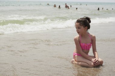 Pembe bikinili kız güneşli bir yaz gününde kumsalda dalgalarla mutlu mesut oynuyor, Vera, İspanya