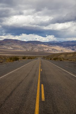 Arka planda beyaz bulutlar olan bir yolun dikey çekimi